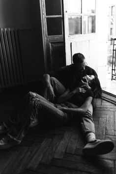 black and white photograph of two people sitting on the floor with their hands around each other