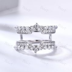 two white gold rings with diamonds in them on top of a white surface, the middle one has an open band