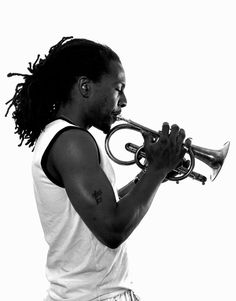 a man with dreadlocks playing a trumpet in front of a white background, black and white photograph