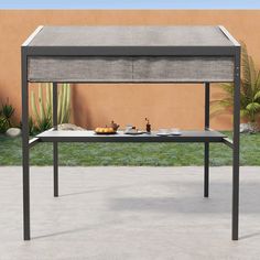 an outdoor table with food and drinks on it in front of a desert wall,