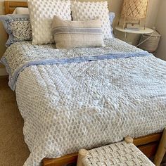 a bed with blue and white comforter in a bedroom next to a lamp on a nightstand