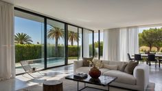 a living room filled with furniture next to large glass doors and windows that look out onto the pool