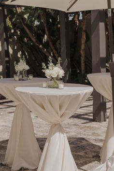 the table is set with white flowers and umbrellas