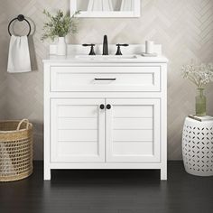 a white bathroom vanity with two mirrors above it and a basket on the floor next to it