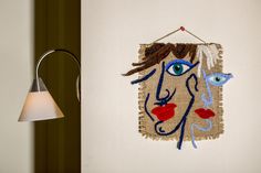 a wall hanging with an image of a woman's face on it and a lamp next to it