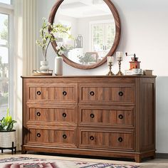 a wooden dresser with a round mirror above it