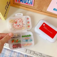 a person holding a plastic container with food in it on a table next to a keyboard