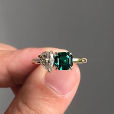 a person holding an emerald and diamond ring