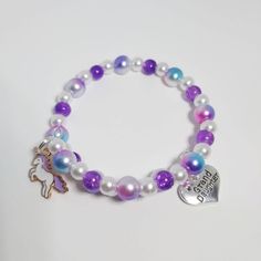 She will feel magical in this sweet unicorn beaded bracelet.  It is made with purple glass beads, with rainbow and white faux pearls. It is a memory wire wrap bracelet so it will fit a wide range of sizes.  It has a Tibetan Silver Granddaughter charm and an Enamel Unicorn Charm. The charms can be switched for any of those pictured, if requested. All of my items are handmade in Prince Edward Island, Canada. Shipping Information Shipping to Canada is by letter mail and usually takes about 10 days Adjustable Purple Charm Bracelet For Birthday, Cute Purple Charm Bracelet For Friendship, Cute Purple Beaded Bracelets For Birthday, Cute Purple Jewelry For Friendship, Purple Beaded Charm Bracelet For Friendship, Adjustable Purple Jewelry For Birthday, Purple Letter Beads For Jewelry Making, Adjustable Purple Stretch Bracelet For Birthday, Purple Beaded Bracelet For Birthday