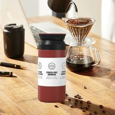 a coffee mug sitting on top of a wooden table next to a cup of coffee