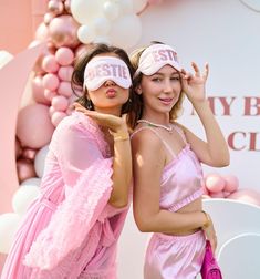 two women in pink dresses and blindfolds posing for the camera