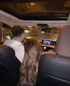 a man and woman sitting in the back seat of a car with their backs to each other