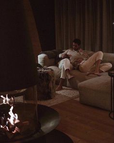 a man and woman sitting on a couch next to a fire place in a living room