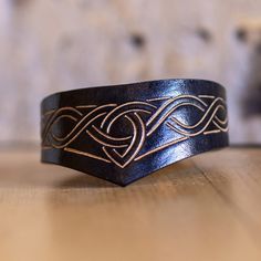 a black and gold ring sitting on top of a wooden table