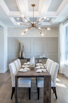 the dining room table is set for six with white chairs and place settings on it