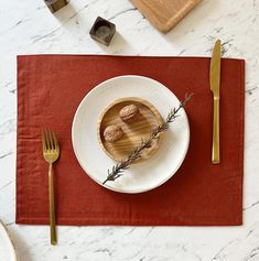 a plate with some food on it next to a fork and knife, along with other items