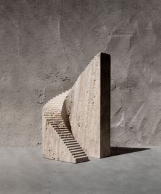 a concrete structure with steps leading up to the top, against a gray wall and cement floor