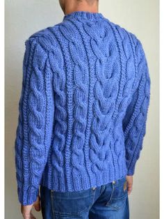 a man wearing a blue cabled sweater looking down at the back of his jacket