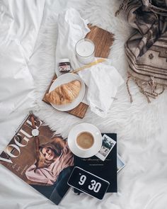 breakfast on a bed with coffee, croissant and magazine