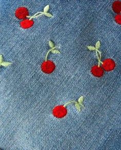 red cherries are embroidered onto the back of a blue jean jacket