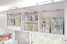 the inside of a kitchen with white cupboards and shelves filled with various craft supplies