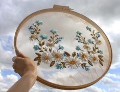 a person holding up a cross - stitch project with blue and white flowers on it