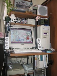 a computer monitor sitting on top of a desk next to a keyboard and speakers in front of a window