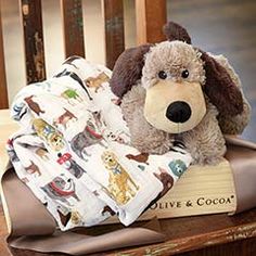 a stuffed dog sitting on top of a book next to a teddy bear and blanket