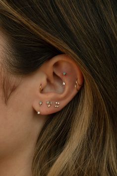 a woman wearing gold ear piercings with small stars on the top of her ears