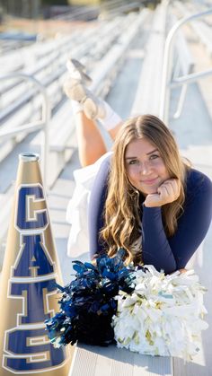 a beautiful young woman laying on top of a wooden floor next to a blue and white cheerleader