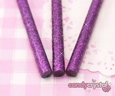 three purple glittered candles sitting on top of a pink tablecloth with white doily