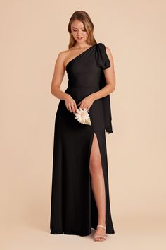 a woman wearing a black one shoulder dress with a slit down the side and a flower in her hand