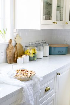 a white kitchen counter top with a pie on it and other items in the background