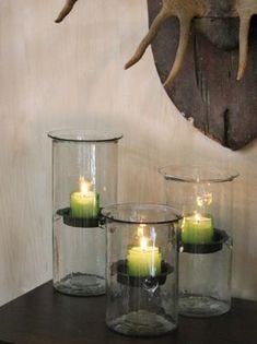 some candles are sitting in glass vases on a table next to a deer head