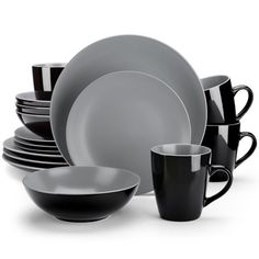 black and white dishes are stacked on top of each other, with cups in the middle