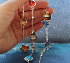 "Beautiful handmade cabochon necklace with solar system. The pattern is protected by the glass cabochon. The base is in silver or antique brass color. The necklace is a shape of a circle. Specifications: - length: you choose - bead size: Mercury, Venus, Earth, Mars, Pluto: 0.39\"; Jupiter, Saturn, Uranus, Neptune: 0.47\", Sun: 0.55\" - will resist rain/snow Here you can find pictures of this item in silver: https://www.etsy.com/listing/489986991/planet-necklace-necklace-with-planets ------------ Nickel-free Adjustable Space-themed Jewelry, Space-themed Silver Round Pendant Necklace, Cosmic Necklace, Solar System Jewelry, Nebula Necklace, Planets Solar System, Solar System Necklace, Galaxy Necklace, Galaxy Pendant