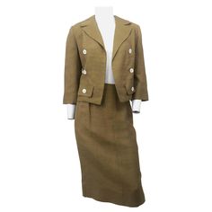 Late 1950s to early 1960s muted gold I. Magnin raw silk suit with abalone shell buttons, peak lapel collar, faux pockets, and glove-length sleeves. The jacket is bolero style. The skirt has a straight silhouette and has a zip closure along the side. Vintage Fitted Skirt Suit With Notch Lapel, Vintage Skirt Suit With Buttons For Office, Vintage Office Skirt Suit With Buttons, Retro Formal Skirt Suit With Buttons, Vintage Formal Skirt Suit With Button Closure, Vintage Skirt Suit With Button Closure For Formal Occasions, Fitted Vintage Suits For Workwear, Semi-formal Fitted Suits With Gold Buttons, Fitted Suits With Gold Buttons For Semi-formal Occasions