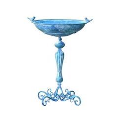 a blue metal bowl on a stand with an ornate design around the rim and feet