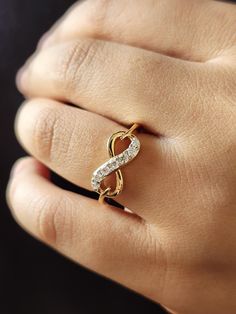 a woman's hand with a gold and white diamond ring on her left hand