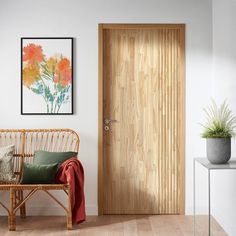 a wooden door in a white room next to a wicker bench and potted plant