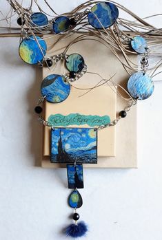 a necklace with blue and green designs hanging from it's side on a white surface