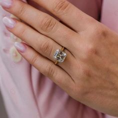 a woman's hand with a diamond ring on her left hand, wearing pink shirt