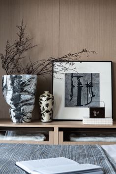 two vases sitting on top of a wooden shelf next to a book and photo