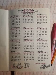 an open notebook with a calendar on it and a pink pen next to the page