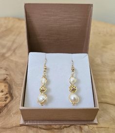 About this product: Our Freshwater Pearl Earrings are a dainty, opulent accessory that dangles lightly from your ears. Pearls are used as the main centerpiece to this lovely set. It is then accented by 14k Filigree Beads and 925 Gold Earring wires. We've made these earrings with lightweight and allergen-friendly materials, so you can have your own beauty naturally accented without sacrificing any comfort. This product will come in the displayed gift box along with a polishing cloth.   What we lo Elegant Wire-wrapped Yellow Gold Pearl Earrings, Elegant Wire Wrapped Earrings For Formal Occasions, Elegant Yellow Gold Wire Wrapped Pearl Earrings, Elegant Gold Wire Wrapped Jewelry, Elegant Formal Wire Wrapped Jewelry, Yellow Gold Wire Wrapped Pearl Earrings Gift, Elegant Hypoallergenic Jewelry With Round Beads, Elegant Wire Wrapped Drop Linear Earrings, Gold Wire Wrapped Earrings For Formal Occasions