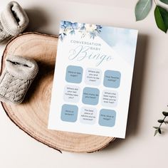 a baby shower game is displayed on a wooden tray next to shoes and greenery