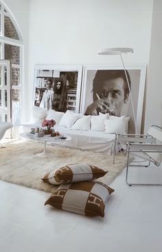 a living room filled with white furniture and pictures on the wall above it's windows