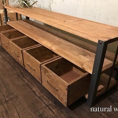 a wooden table with drawers underneath it on the floor next to a white wall and wood floors