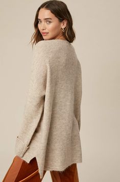 So chic and effortless, this slouchy, oversized tunic-style sweater features a v-neckline and dropped wide sleeves for added shape. -Available in Stone & Misty Blue -Waffle textured -V-neck -Oversized fit -Soft touch eyelash two tone yarn -Long sleeve with folded cuffs -Side slits -Ribbed on hem -Content: 74% Acrylic 22% Polyester 4% Lycra -Hand was cold/Line dry -Imported -Model is 5 8" 32-24-34 and wearing a size Small Oversized Chunky Knit V-neck Sweater For Fall, Oversized Chic V-neck Sweater, Oversized V-neck Sweater For Loungewear, Oversized V-neck Chic Sweater, Beige V-neck Sweater For Fall Loungewear, Oversized V-neck Sweater For Layering, V-neck Cardigan With Soft Texture For Loungewear, Soft V-neck Cardigan For Loungewear, Soft Texture V-neck Cardigan For Loungewear