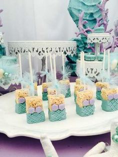 there are many desserts on the table with purple and blue decorations around them,